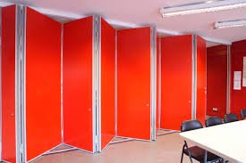 Red movable partition panels closed across a room laid out with tables and chairs.