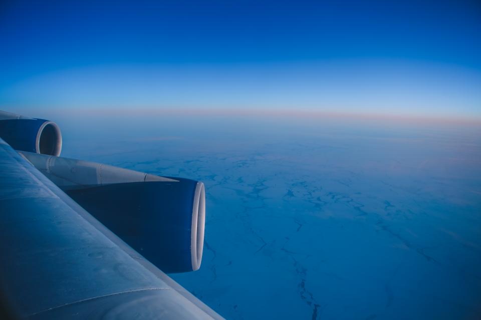 The wing of a four-engine widebody aircraft seen in flight above cloud.